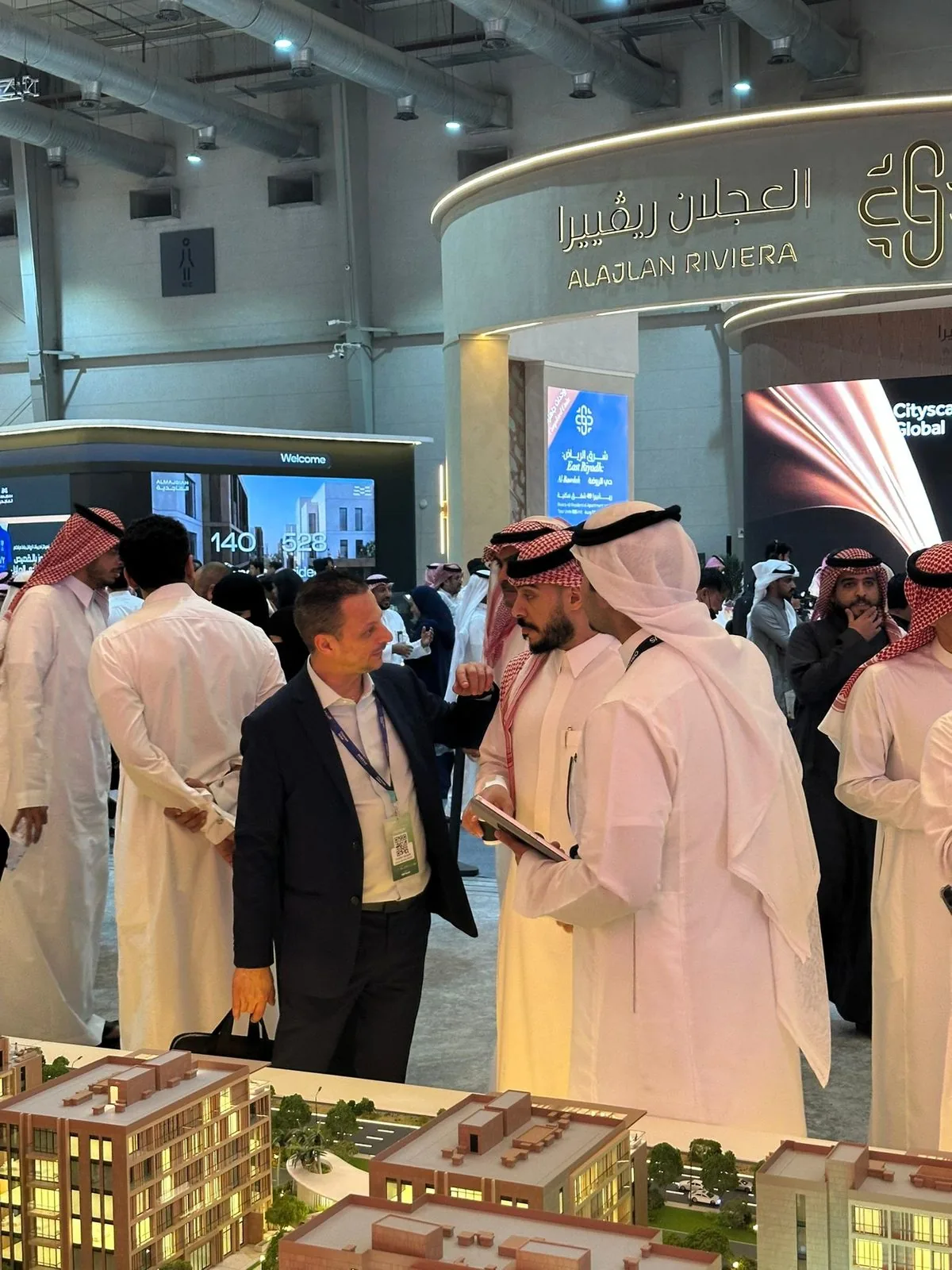 A meeting with developers beside an architectural model in Riyadh.